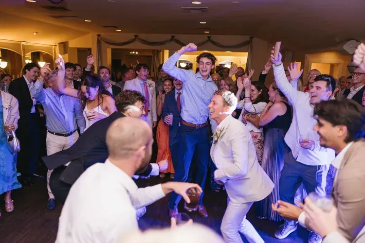 People dancing joyfully at a lively indoor party with raised arms and warm lighting