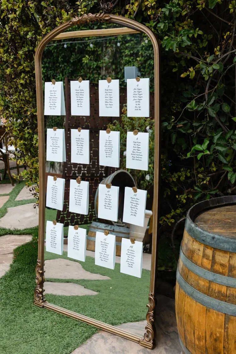 Decorative arched frame with hanging cards beside a wooden barrel outdoors