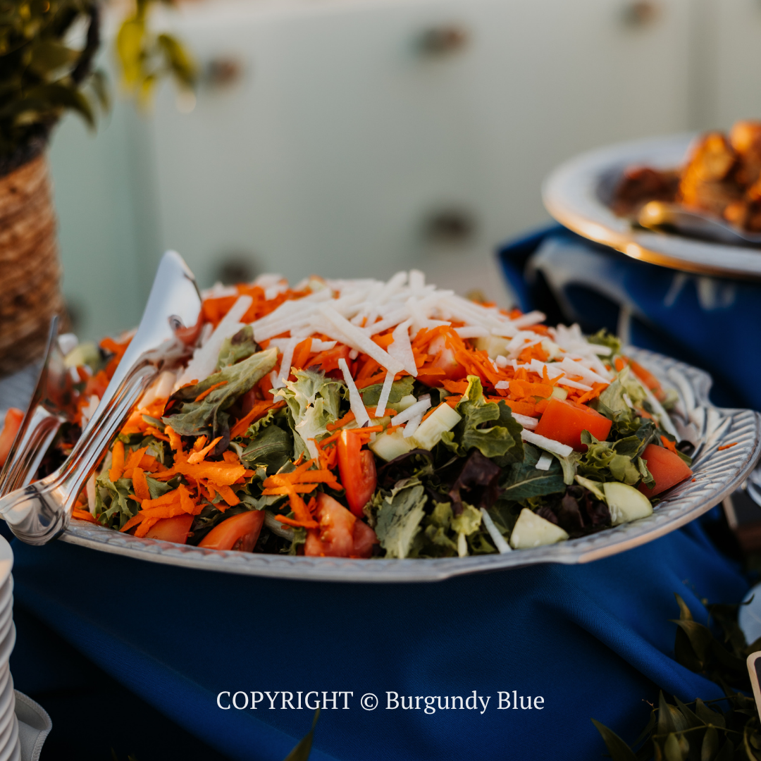 Colorful chopped salad with shredded carrots and cheese on a blue tablecloth, served on a white plate