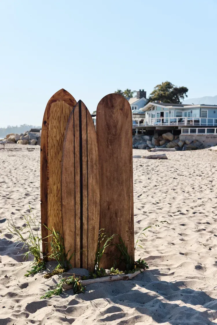 Two weathered wooden posts on a sandy beach with oceanfront houses in the background