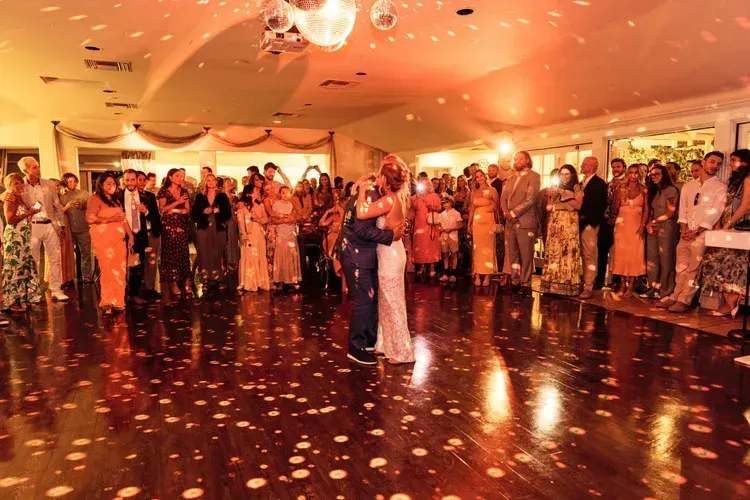 Couples dancing in a warmly lit ballroom with confetti on the floor and guests watching շուրջ