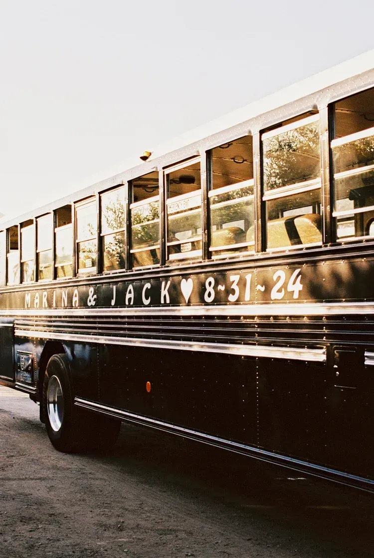 Black school bus parked on a street, side windows lit by warm sunlight.