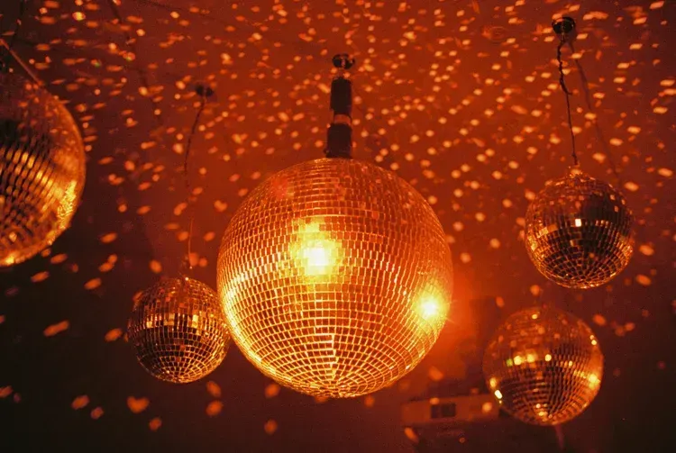 Disco ball lights casting warm orange reflections in a dark club room