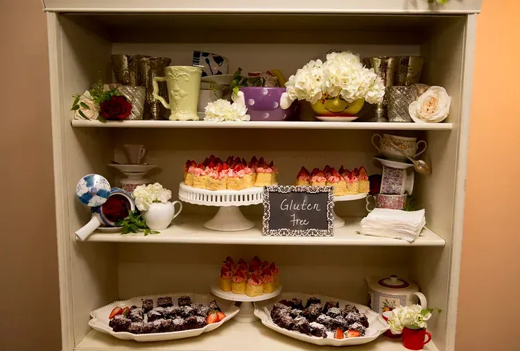 Desserts display with cakes, cupcakes, cookies, and flowers on beige shelves