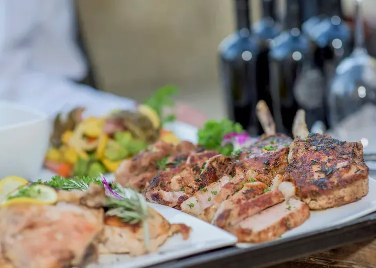 Platter of grilled meat and vegetables with garnishes at a buffet table