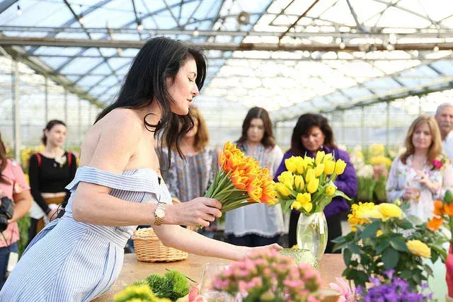 Women arranging colorful flowers in a bright greenhouse