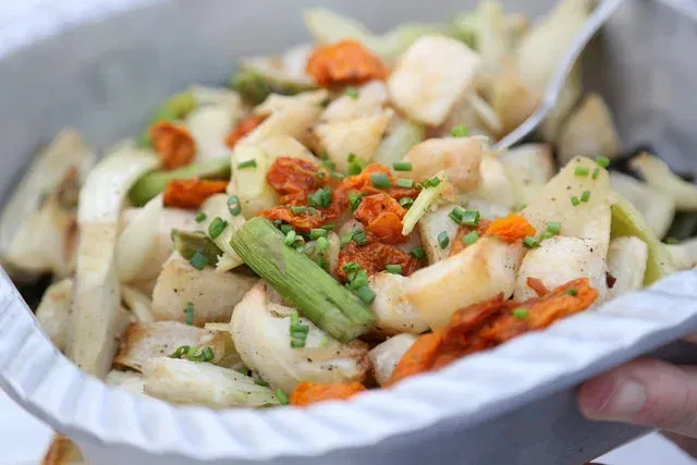 Tray of sliced potatoes topped with herbs and red seasoning, held in a hand