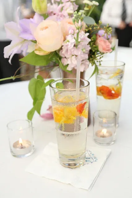 Elegant floral centerpiece with candles and fruit-filled glass vases on a white table