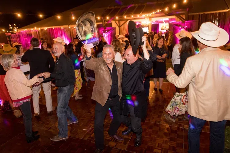 People dancing at a lively indoor party with pink lights and festive decorations