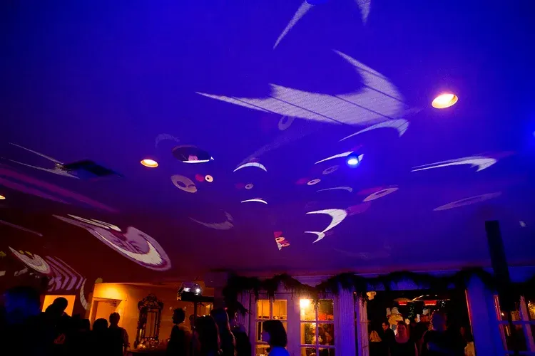 Blue-lit banquet hall ceiling with swirling light projections over a warmly lit crowd below