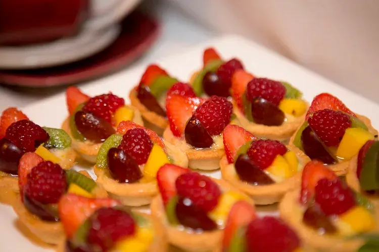 Mini fruit tarts topped with strawberries and kiwi on a tray