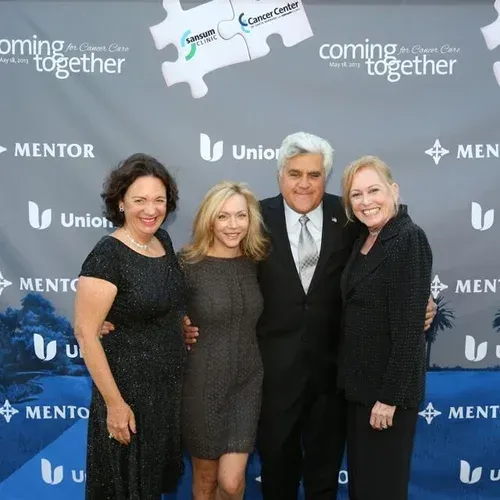 Four people posing at a branded event backdrop in formal black attire
