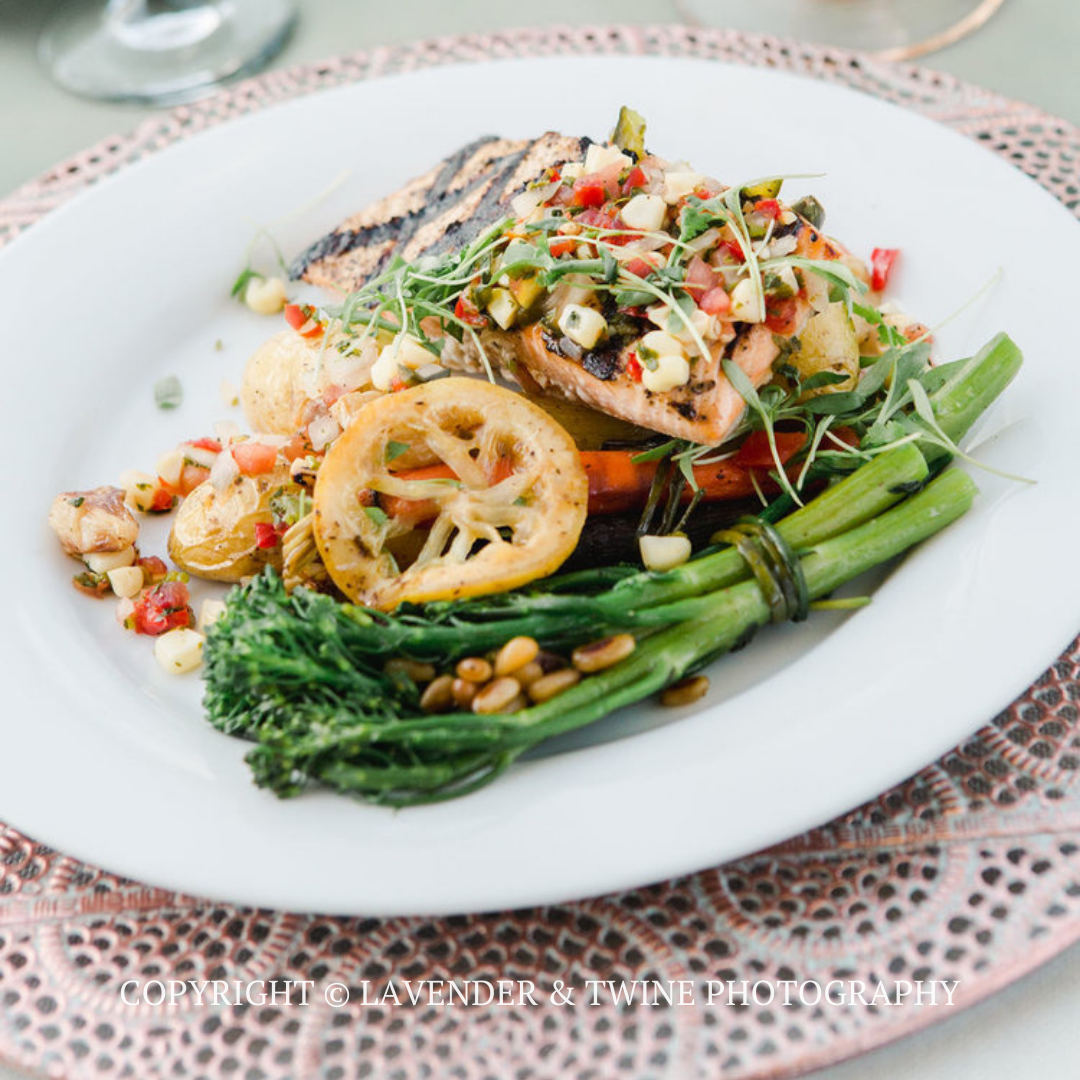 Grilled fish with lemon, green vegetables, and salsa on a white plate