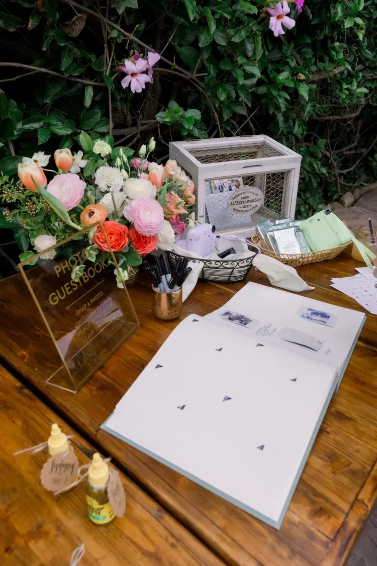 Wedding guestbook table with flowers, cards, and a white sign-in board on a wooden table