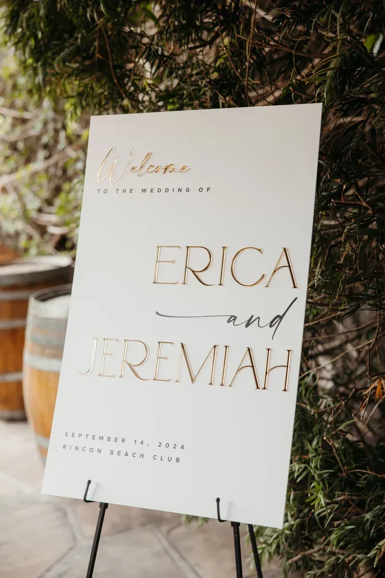 Wedding sign for Erica and Jeremiah on a black easel, with greenery in the background
