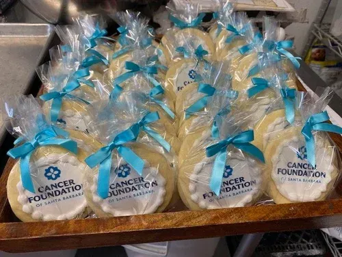 Gift bags with blue ribbons and Cancer Foundation labels arranged on a tray