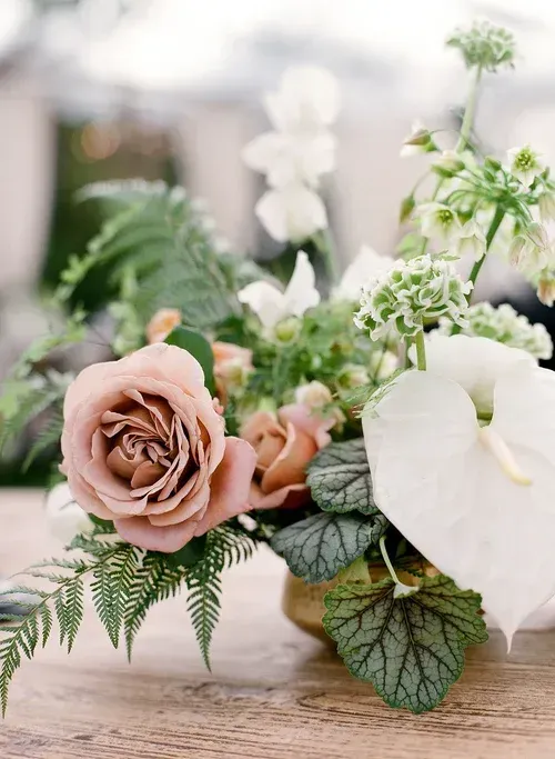 Pink and white roses with greenery arranged on a wooden surface