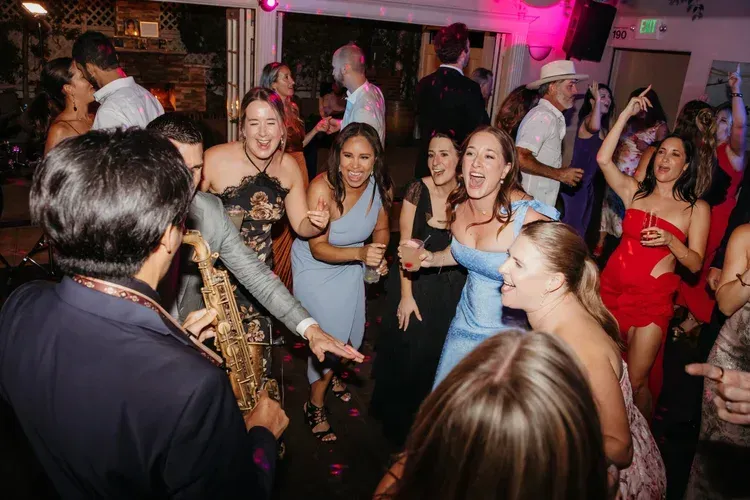 People dancing at a lively indoor party, with music and drinks in a crowded room