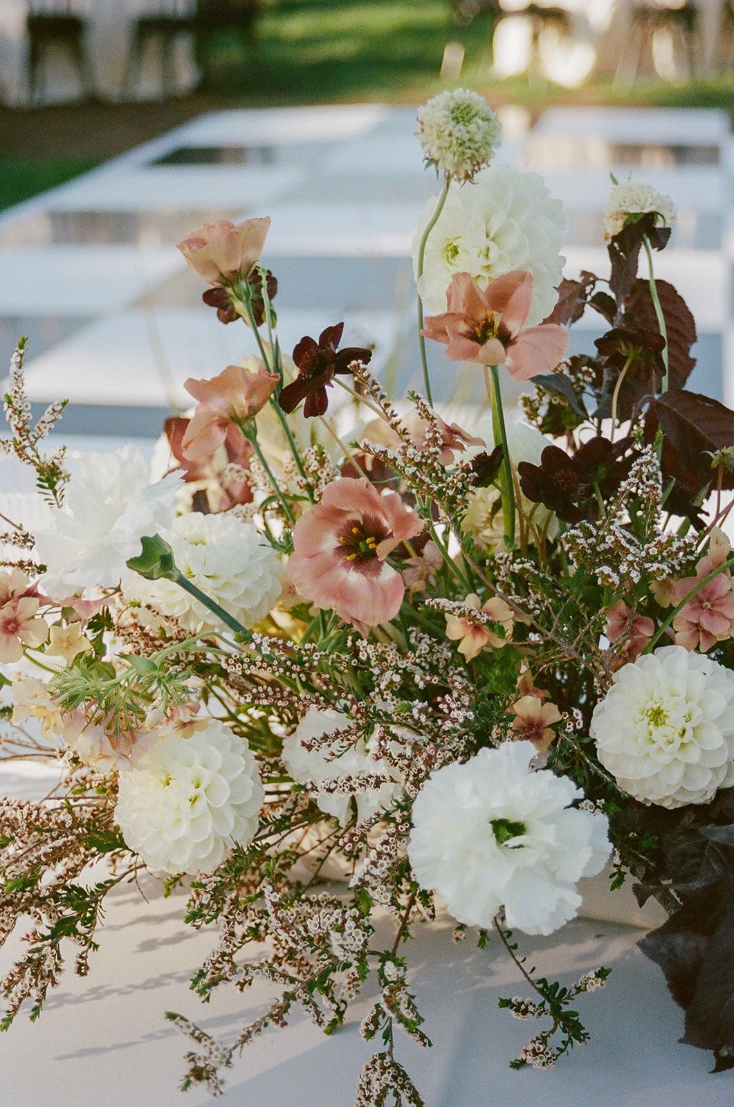 Pastel floral arrangement with white, pink, and burgundy flowers by a poolside table
