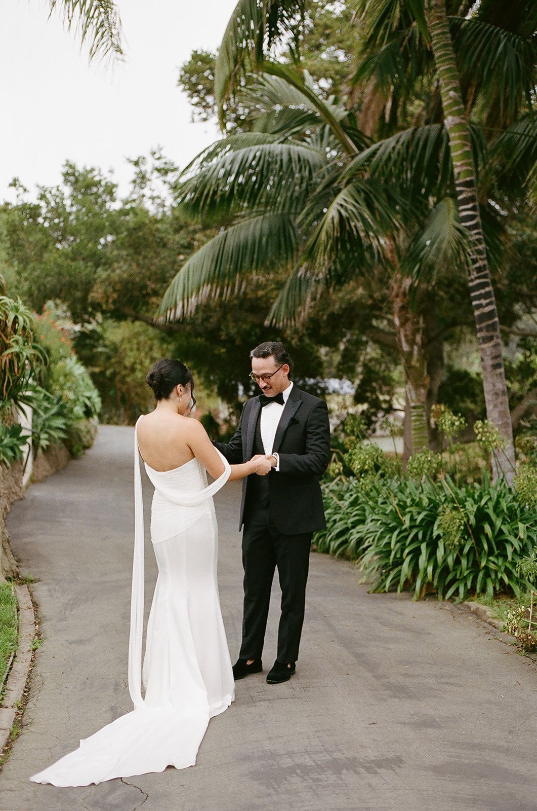 Couple in wedding attire exchanging rings on a garden path