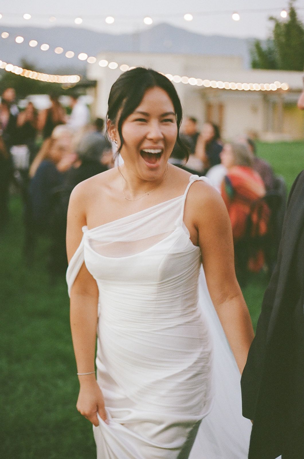 Smiling woman in a white dress at an outdoor evening celebration