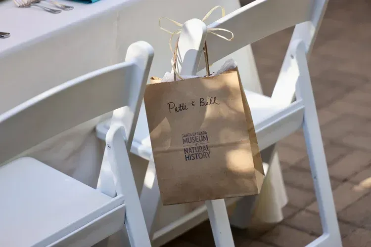 Brown paper gift bag hanging on a white folding chair in a bright room