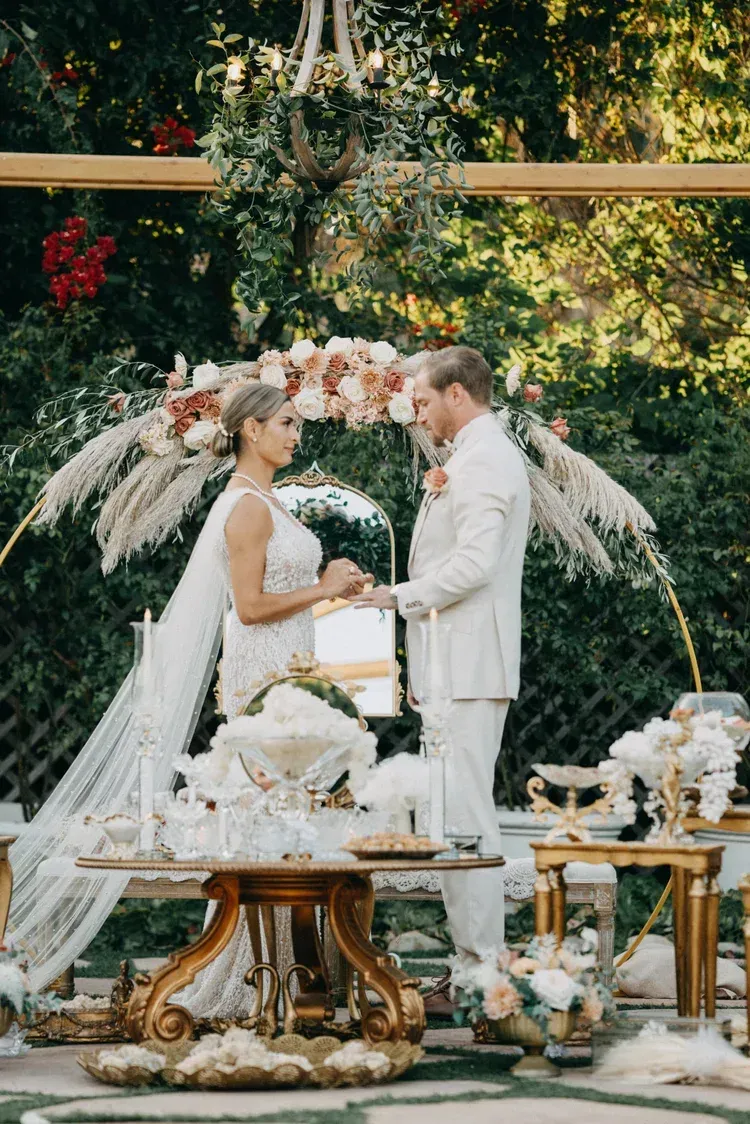 Couple exchanging vows beneath a floral arch in an outdoor garden wedding setup