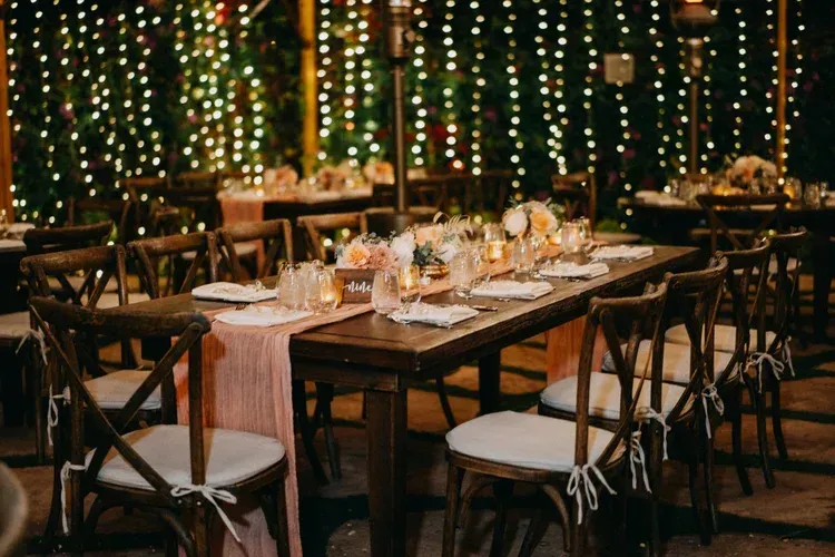 Elegant dining table set with candles and string lights in a cozy outdoor restaurant setting