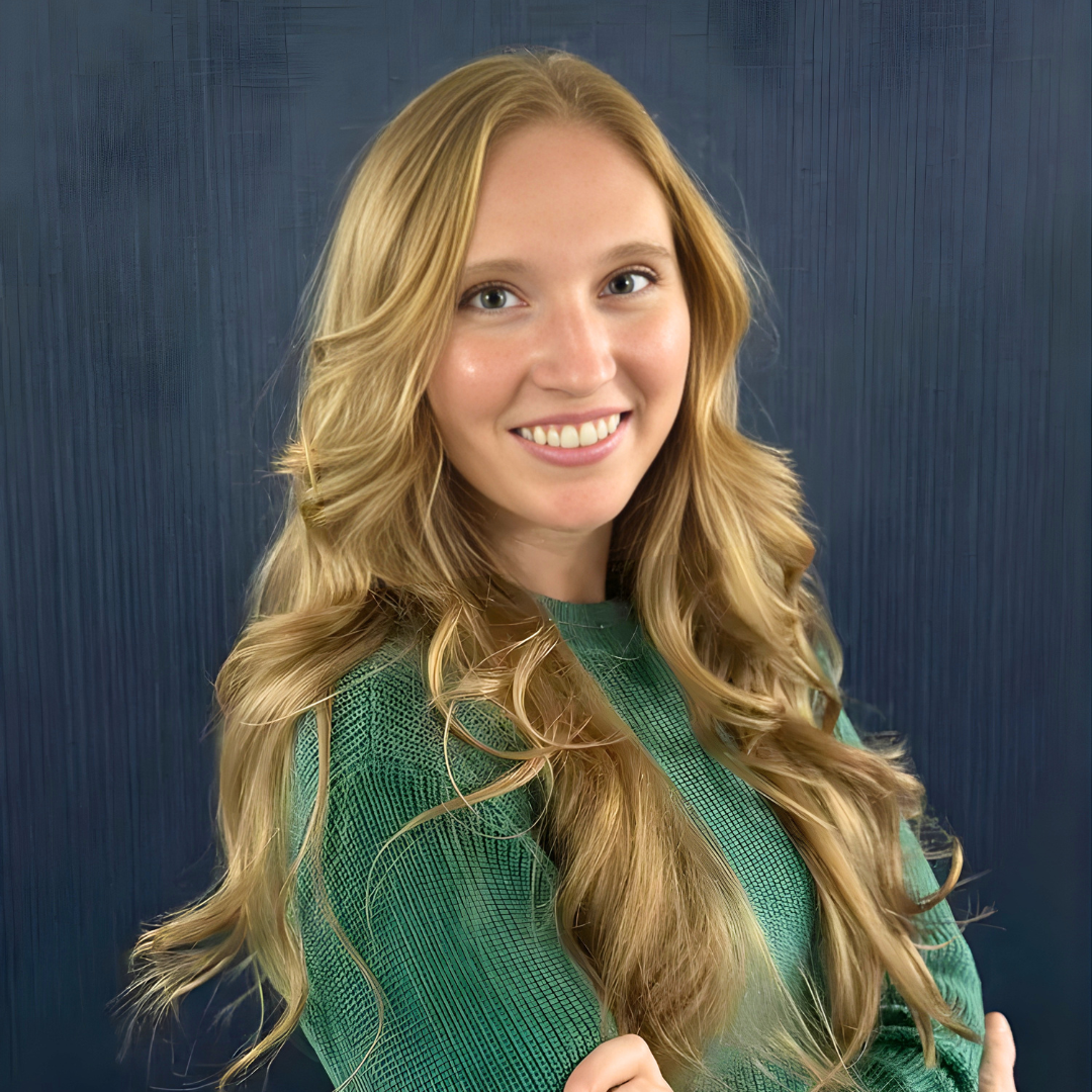 Portrait of a smiling woman in a green sweater against a blue background