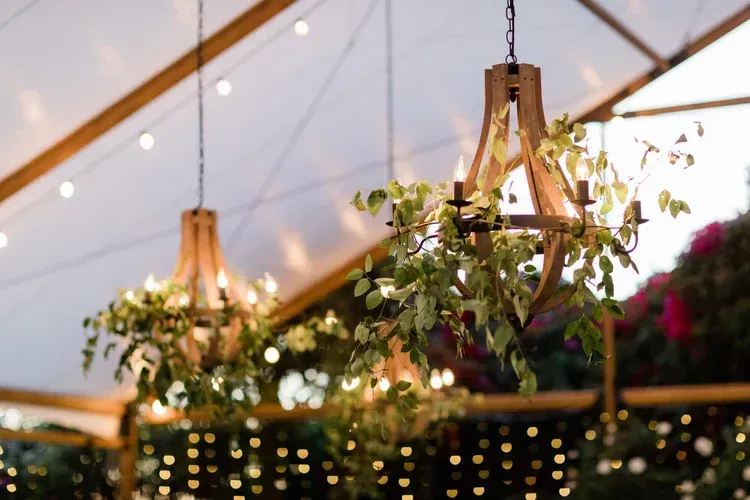 Rustic hanging lanterns and greenery under a white tent with warm string lights