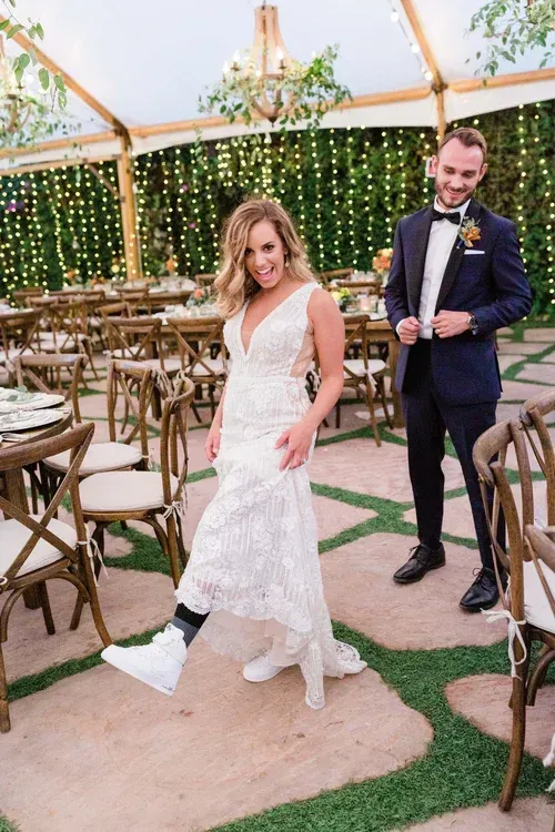 Bride and groom smiling in a decorated outdoor wedding venue, with string lights and greenery backdrop