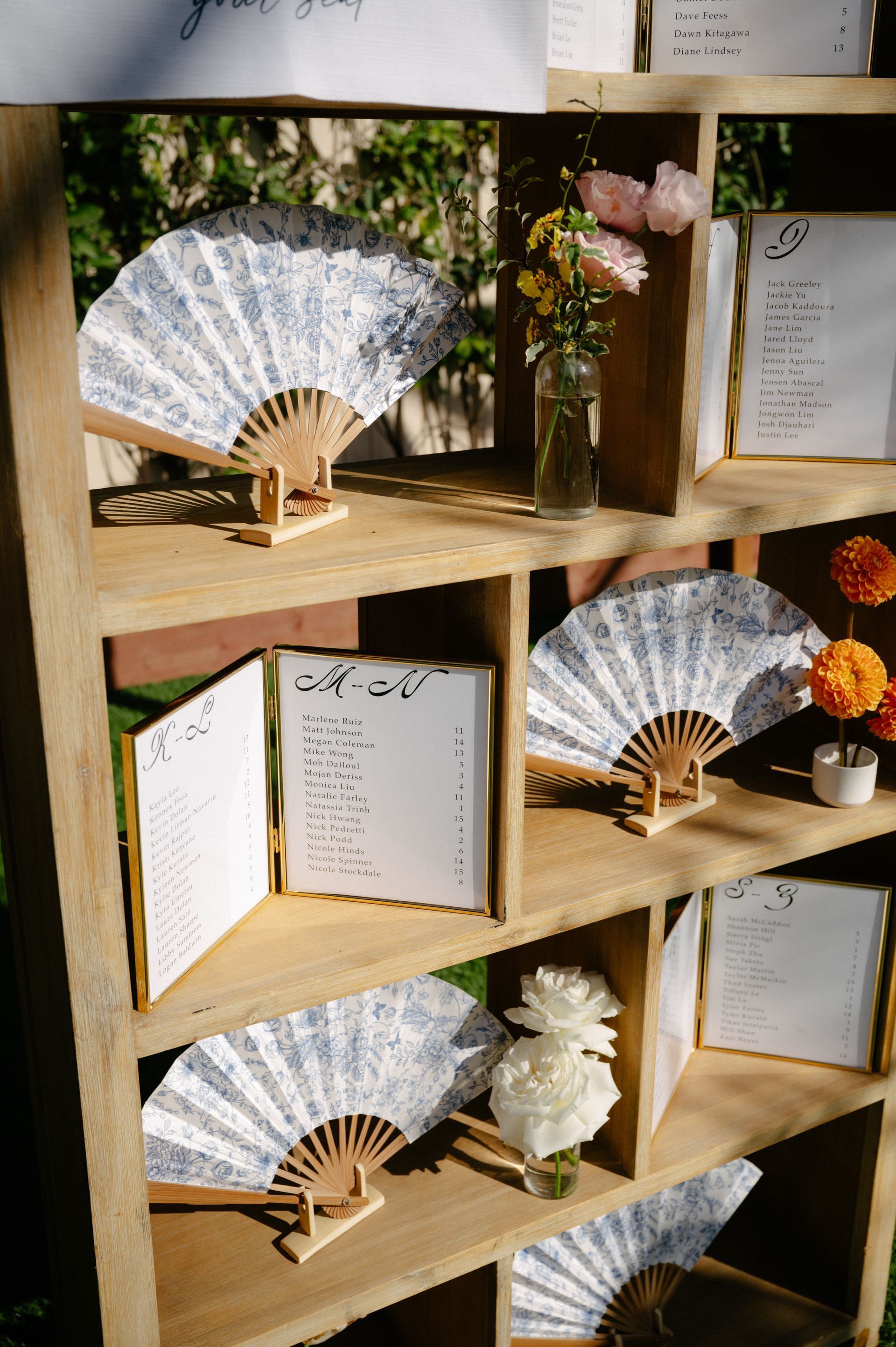Wooden display shelf with white lace fans, flowers, and handwritten cards arranged in cubby spaces