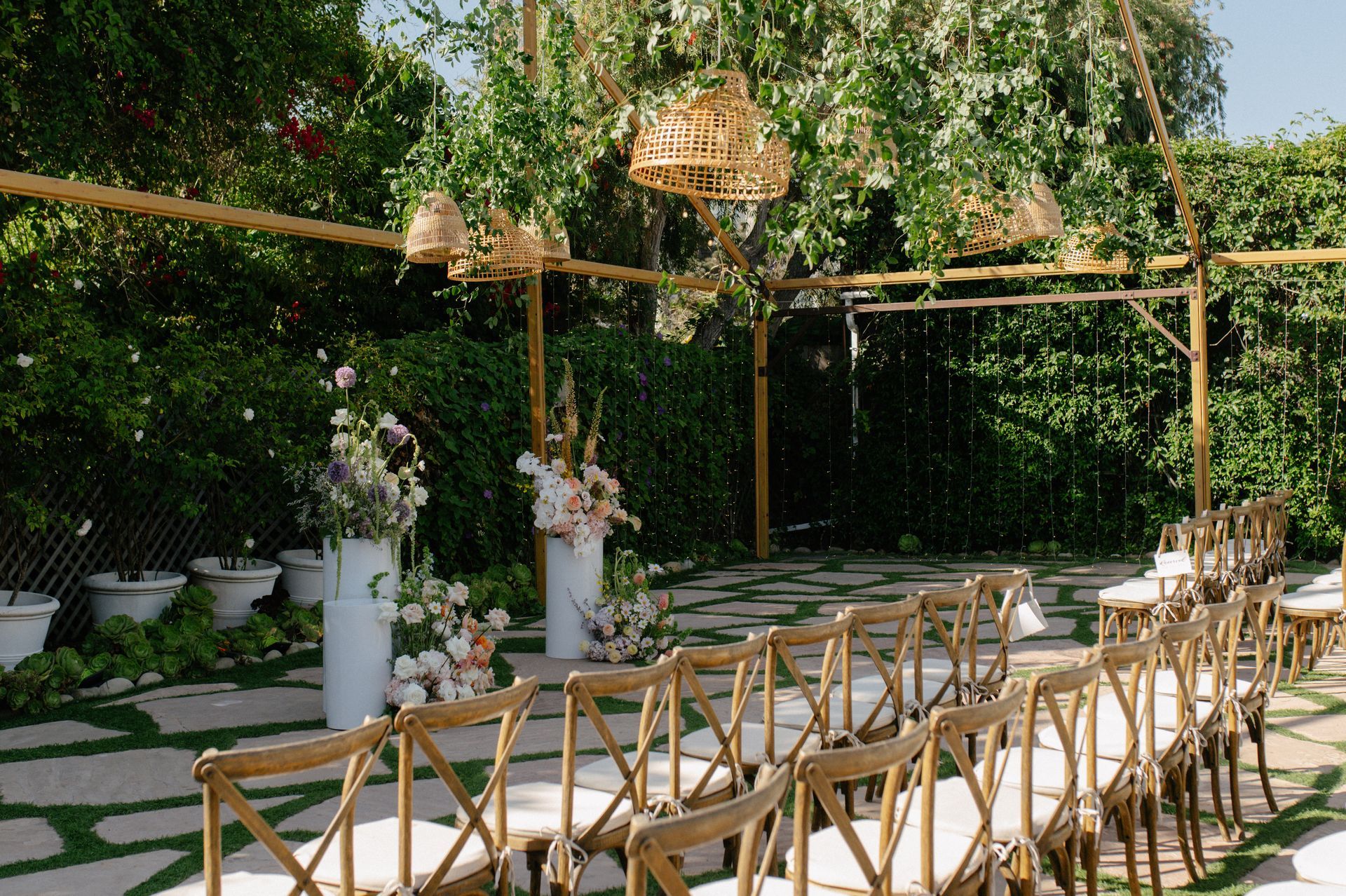 Garden wedding reception with wooden chairs under a floral canopy and string lights