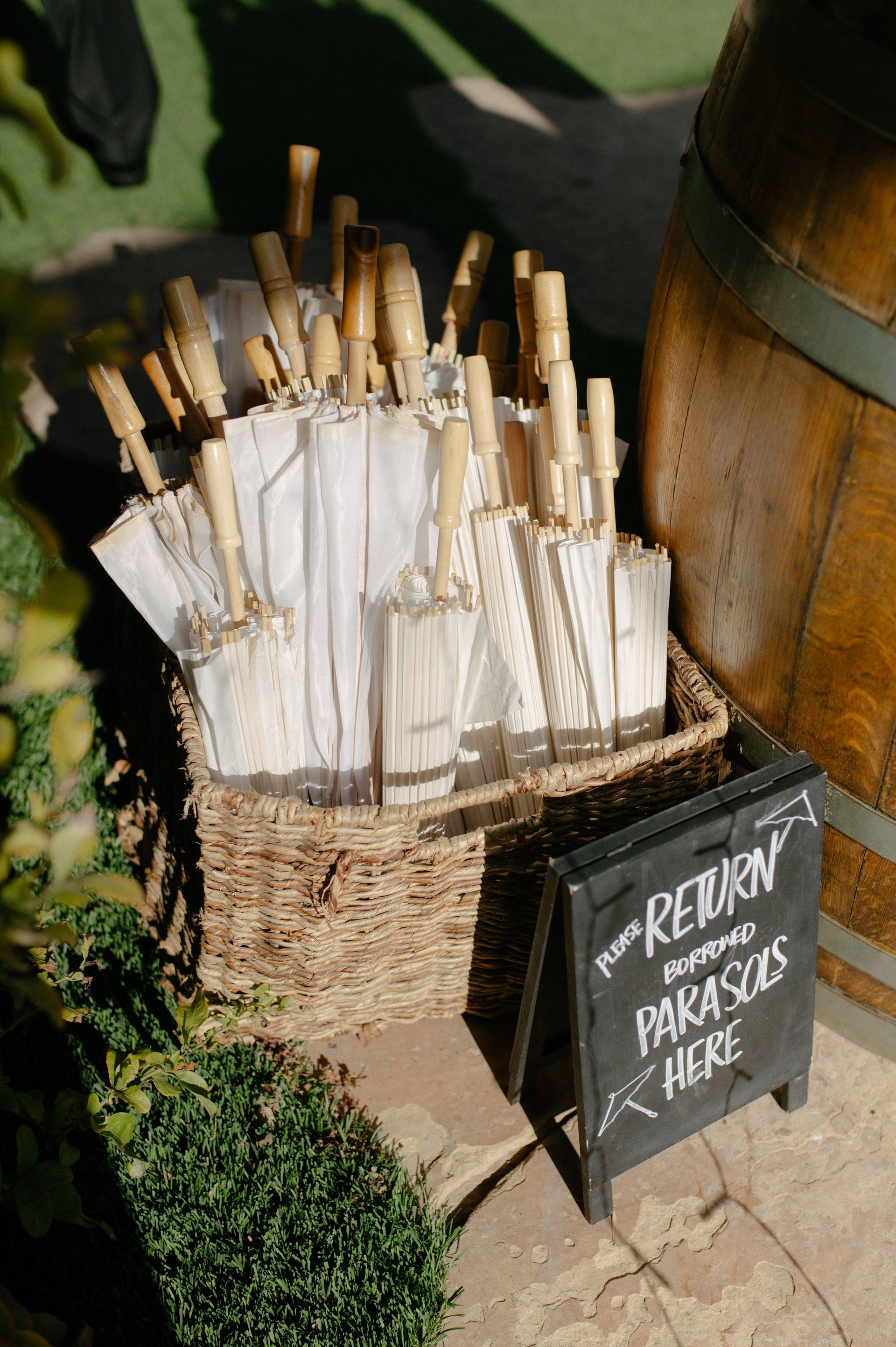 Bundles of white rolled papers in a basket beside a chalkboard sign on a sunny sidewalk