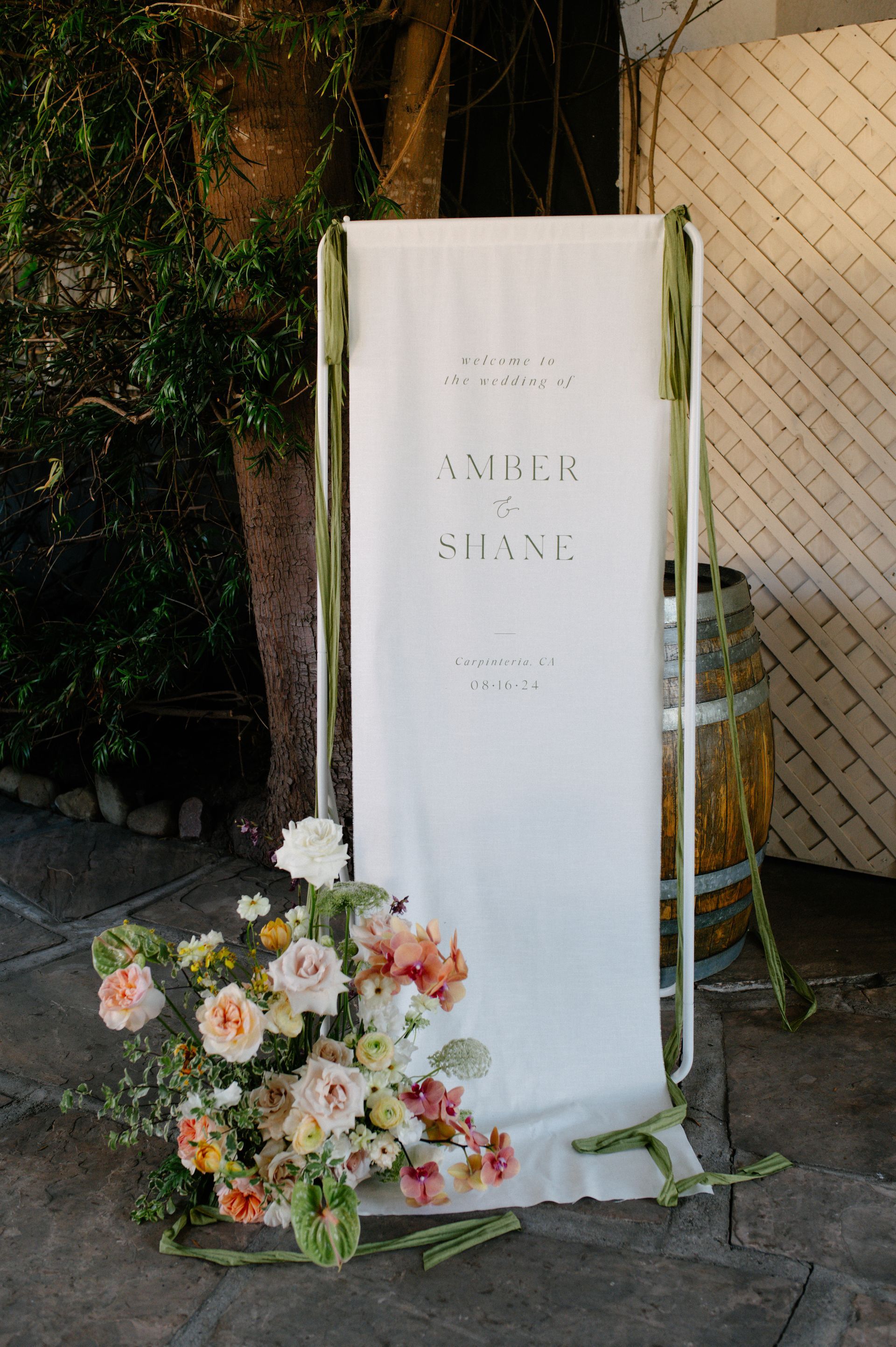White memorial banner with floral arrangement at an outdoor event entrance