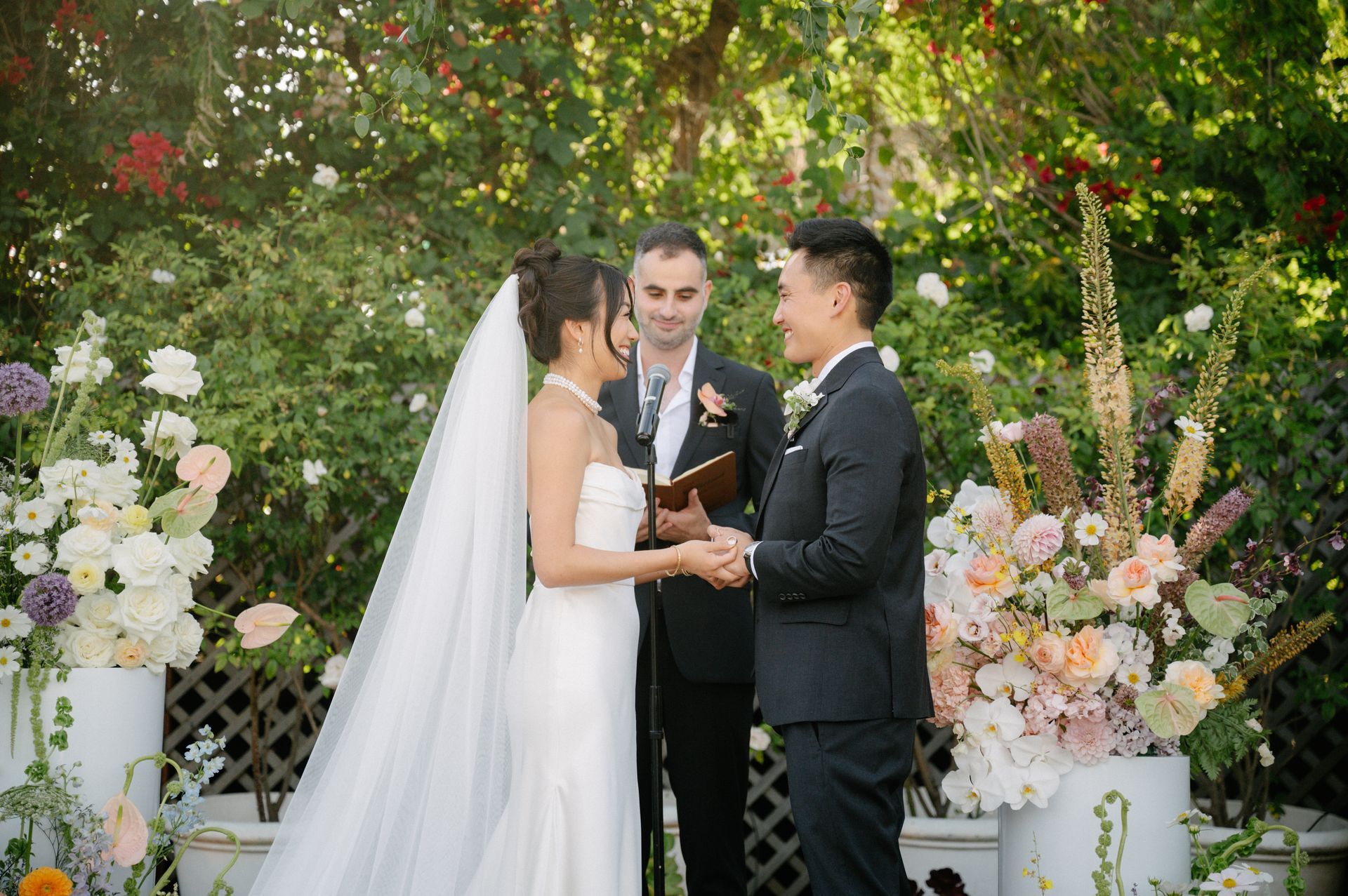 Wedding couple exchanging vows under floral arch in a garden ceremony