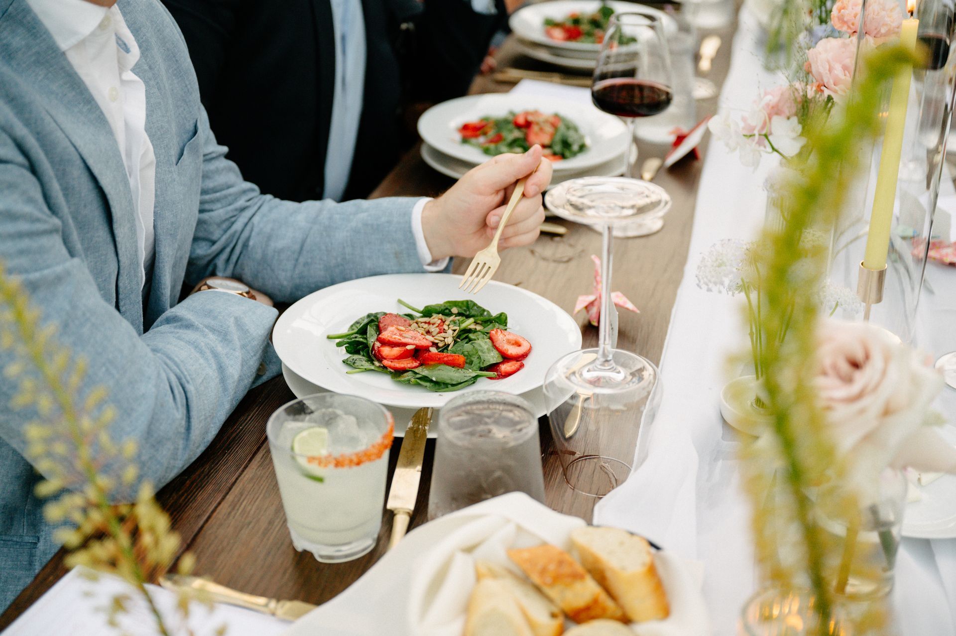 People dining at a table with salad, drinks, and bread in a bright restaurant setting