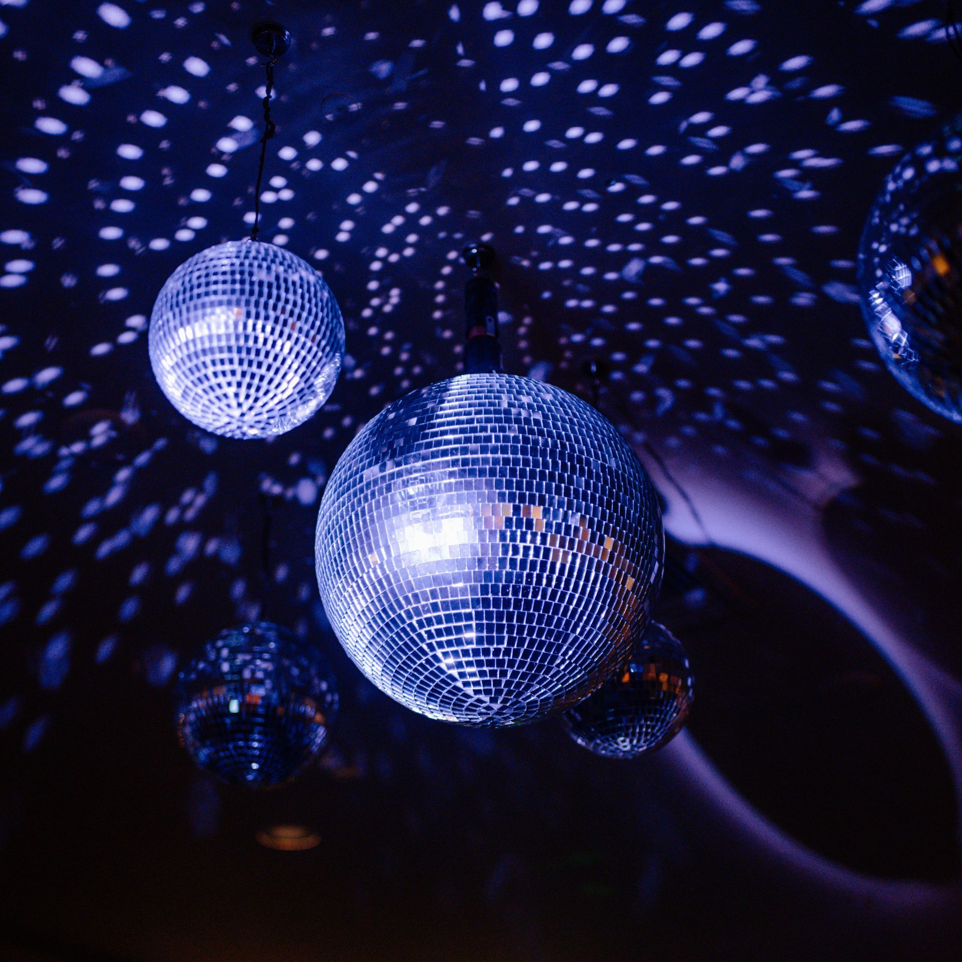 Disco balls casting blue-purple light patterns in a dark room