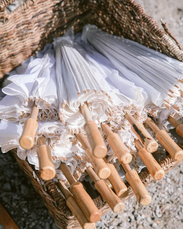 White lace umbrellas with bamboo handles in a wicker basket