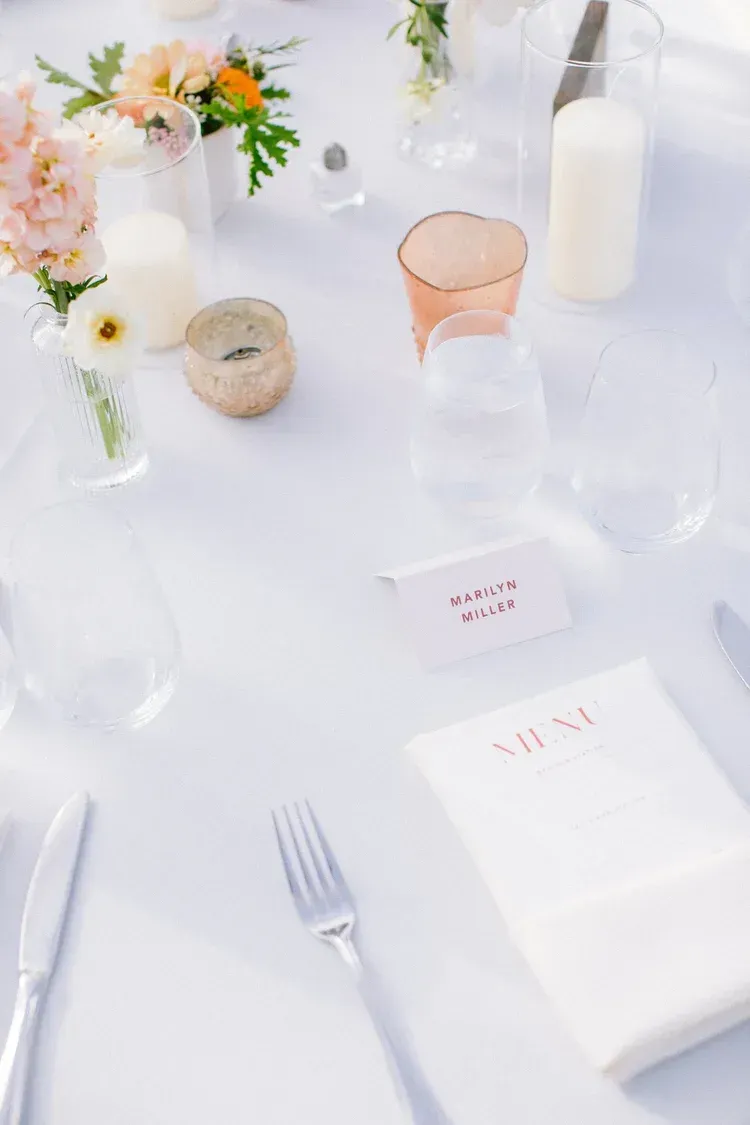 Elegant white table setting with flowers, candles, and glassware for a formal event