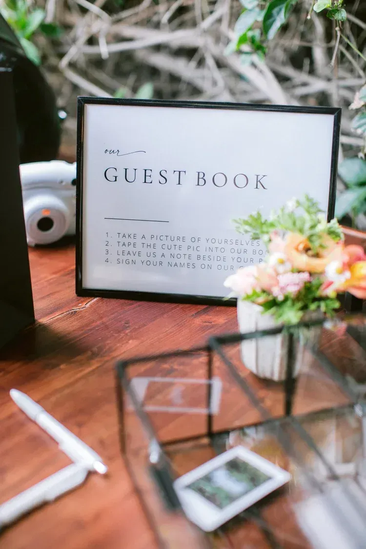 Guest book sign on a wooden table with floral decor and a photo frame