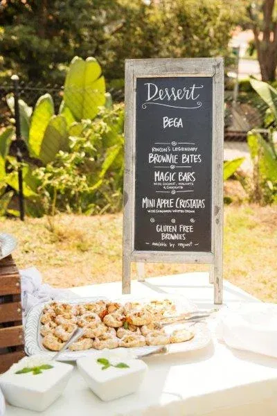 Outdoor dessert table with chalkboard menu and plated pastries in a garden setting
