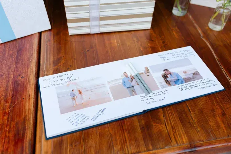 Wedding photo album on a wooden table, open to a spread with beach-themed photos and handwritten notes.