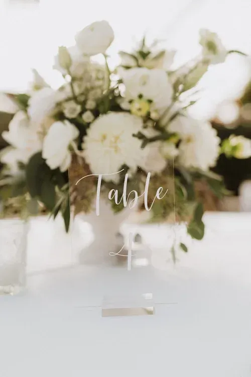 White floral table sign labeled “Table 4” on a reception table