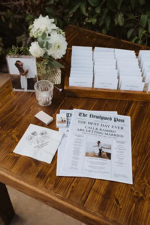 Wedding guestbook and cards arranged on a wooden table with white flowers and a framed photo.