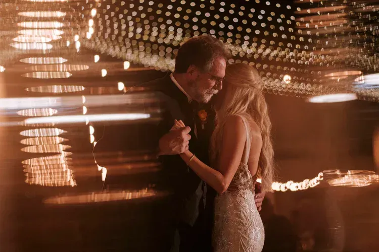 A couple slow dancing in warm, blurred lights at a party
