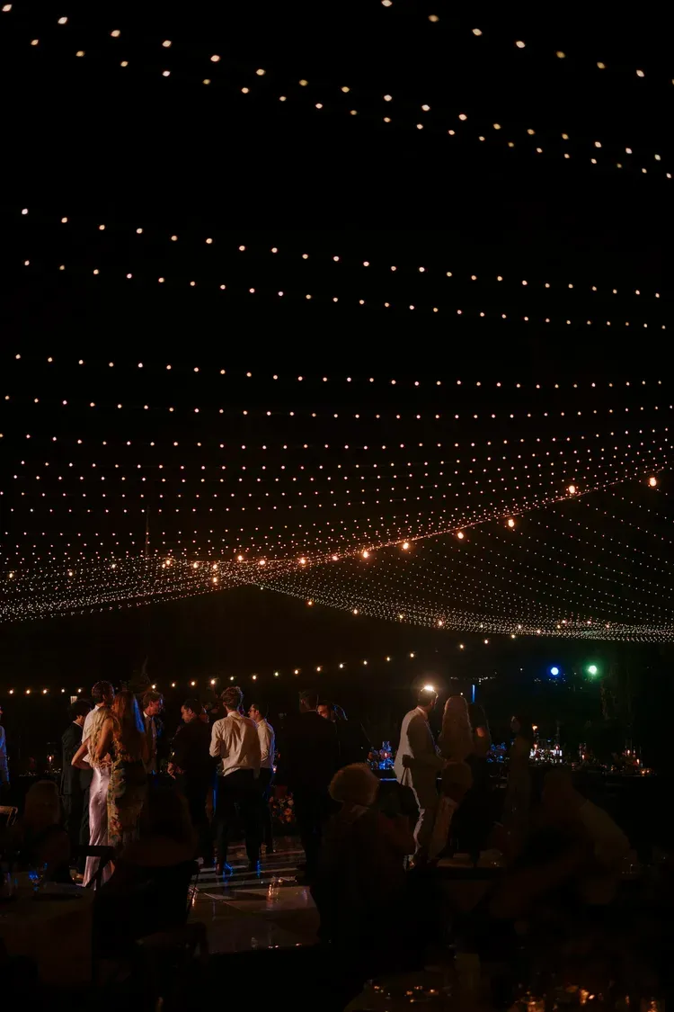 Crowd dancing under string lights at an outdoor nighttime event