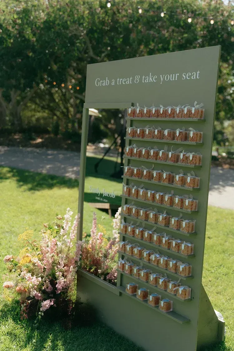 Outdoor seating chart display with rows of small cards beside flowers on a lawn