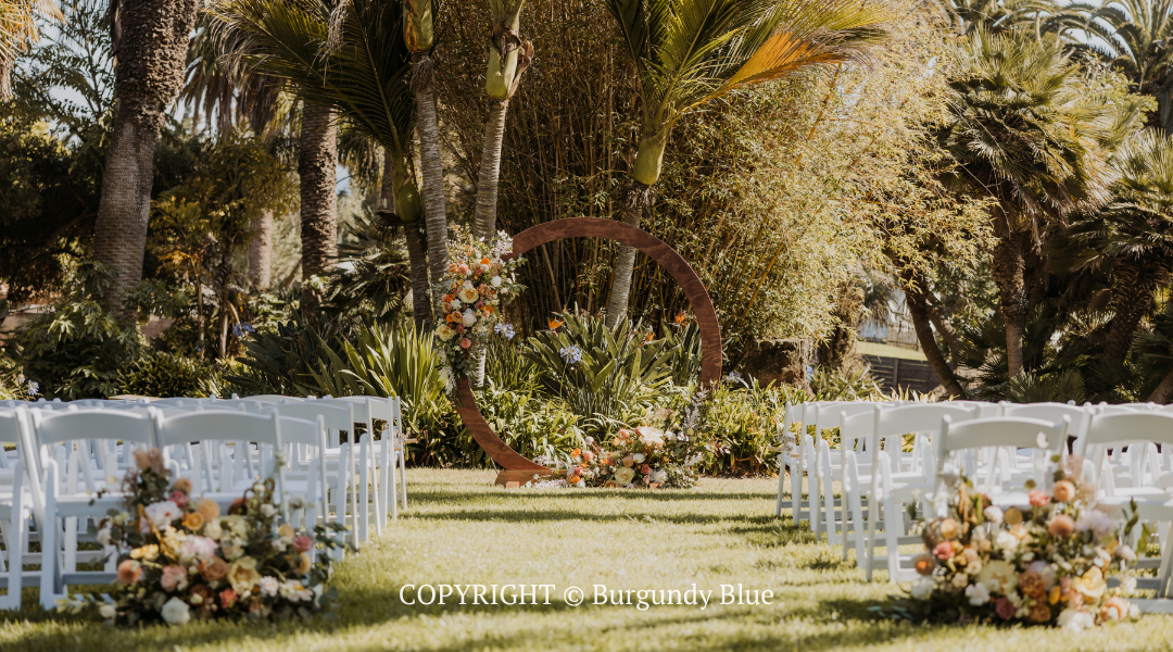 Outdoor wedding aisle with white chairs and floral arrangements in a lush garden