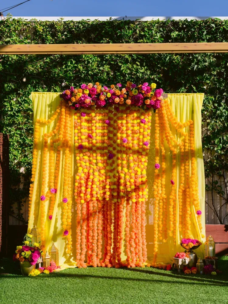 Yellow floral backdrop with pink and orange flower garlands for an outdoor event